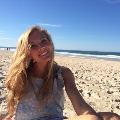 Elora smiling on a sunlit beach beside the ocean